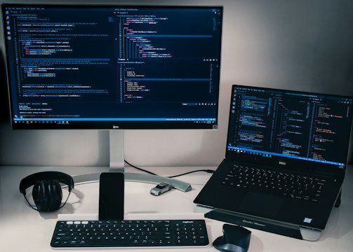 laptop computer beside monitor with keyboard and mouse