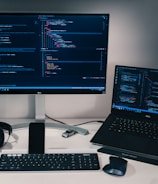 laptop computer beside monitor with keyboard and mouse