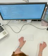 person using macbook pro on white table