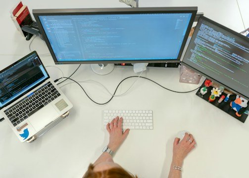 person using macbook pro on white table
